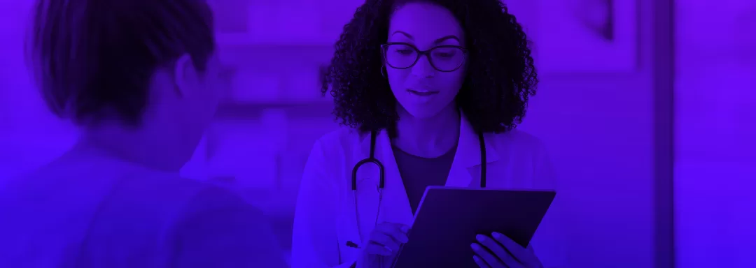 Médica utilizando um tablet em consulta, com um paciente do lado, ambiente de saúde moderno e tecnologia aplicada no atendimento médico.